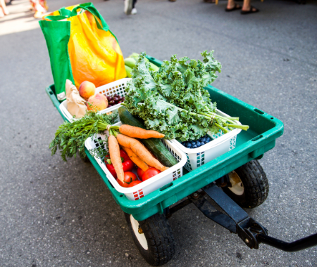 A wagon full of fresh vegetables is being pulled down the street.